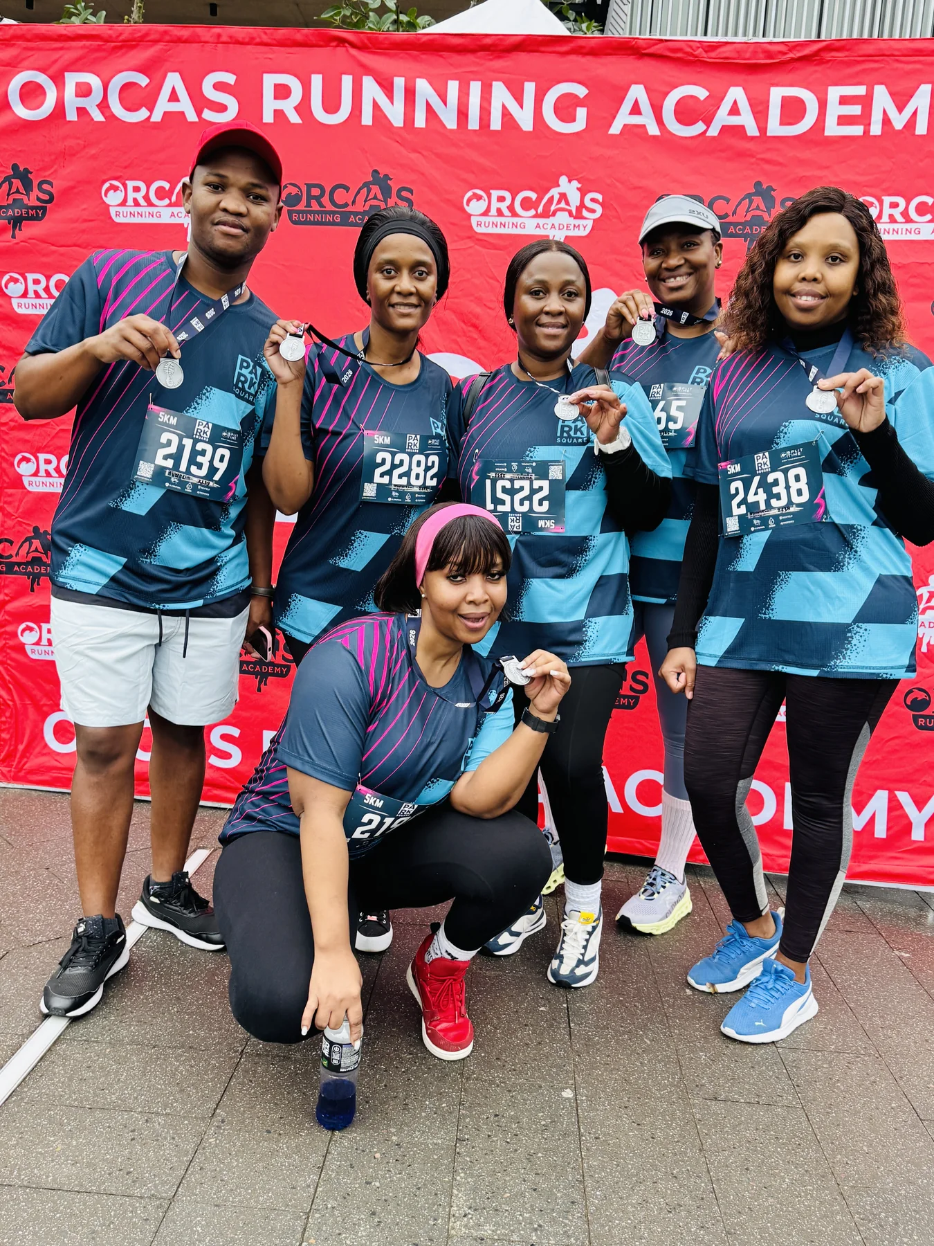 Esihlentu team members holding their Park Square 5K medals